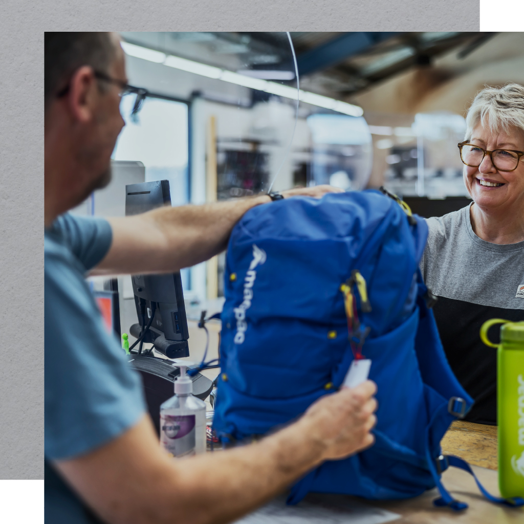 Customer handing blue backpack over Macpac counter