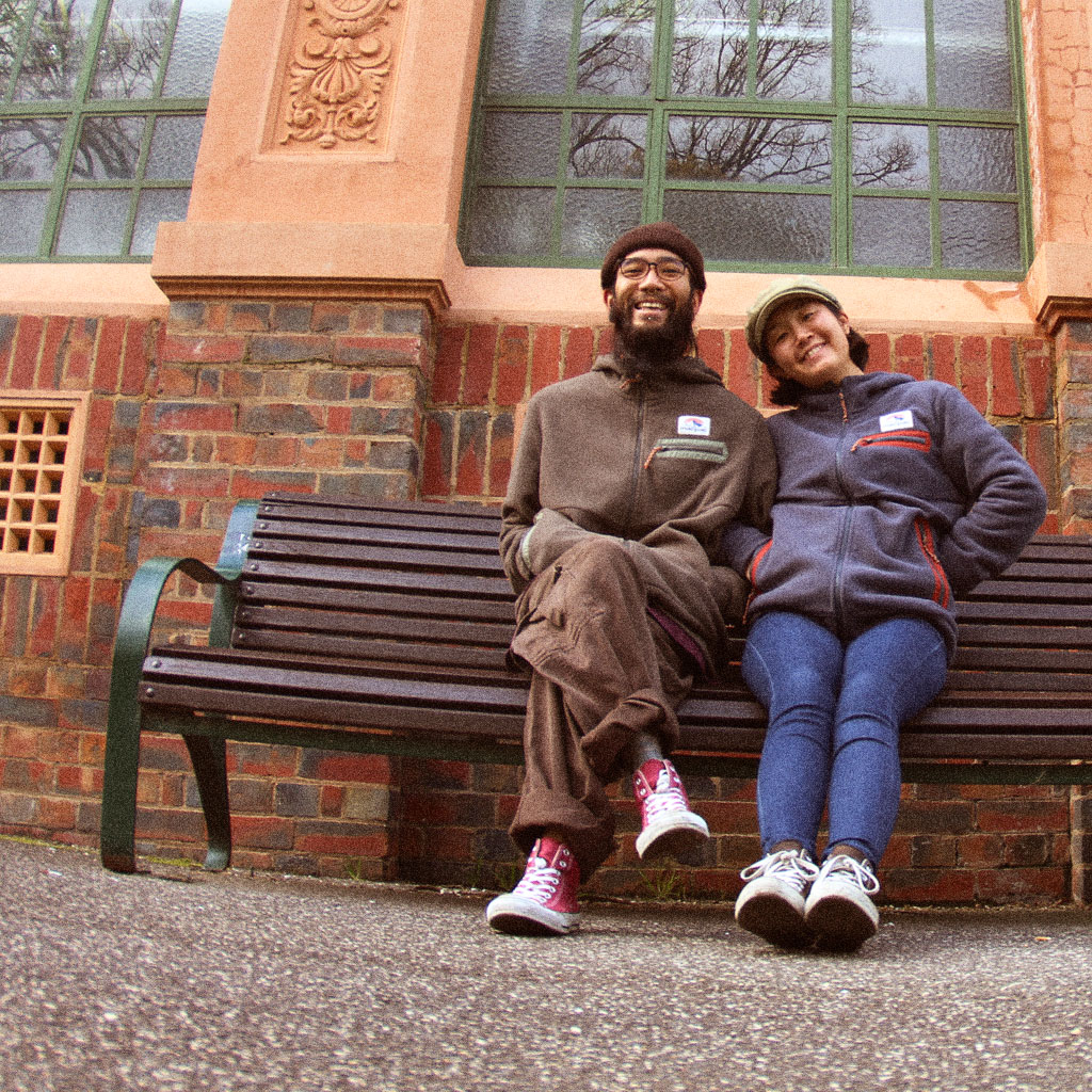 Recycled Content - Happy couple sitting on a bench wearing recycled macpac fleece