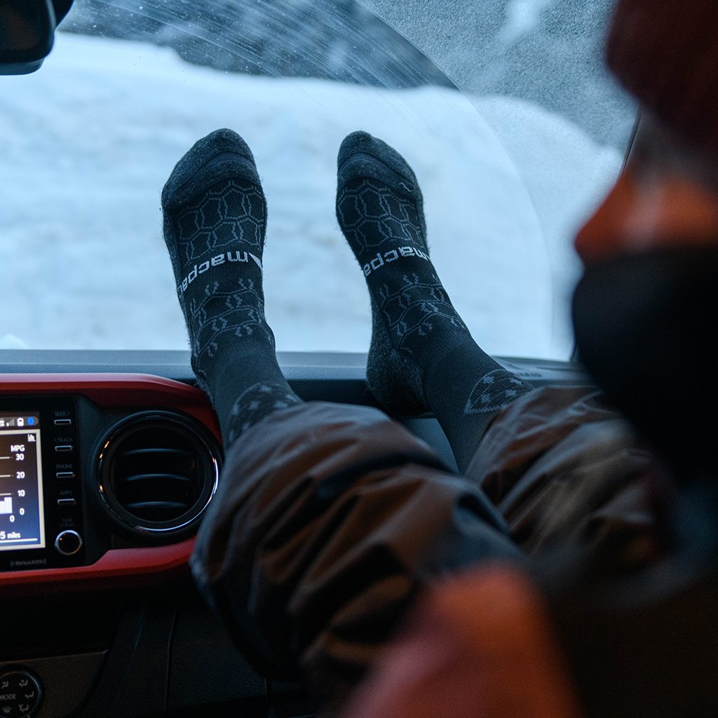 close up of person wearing macpac socks with feet on car dashboard warming feet on heater