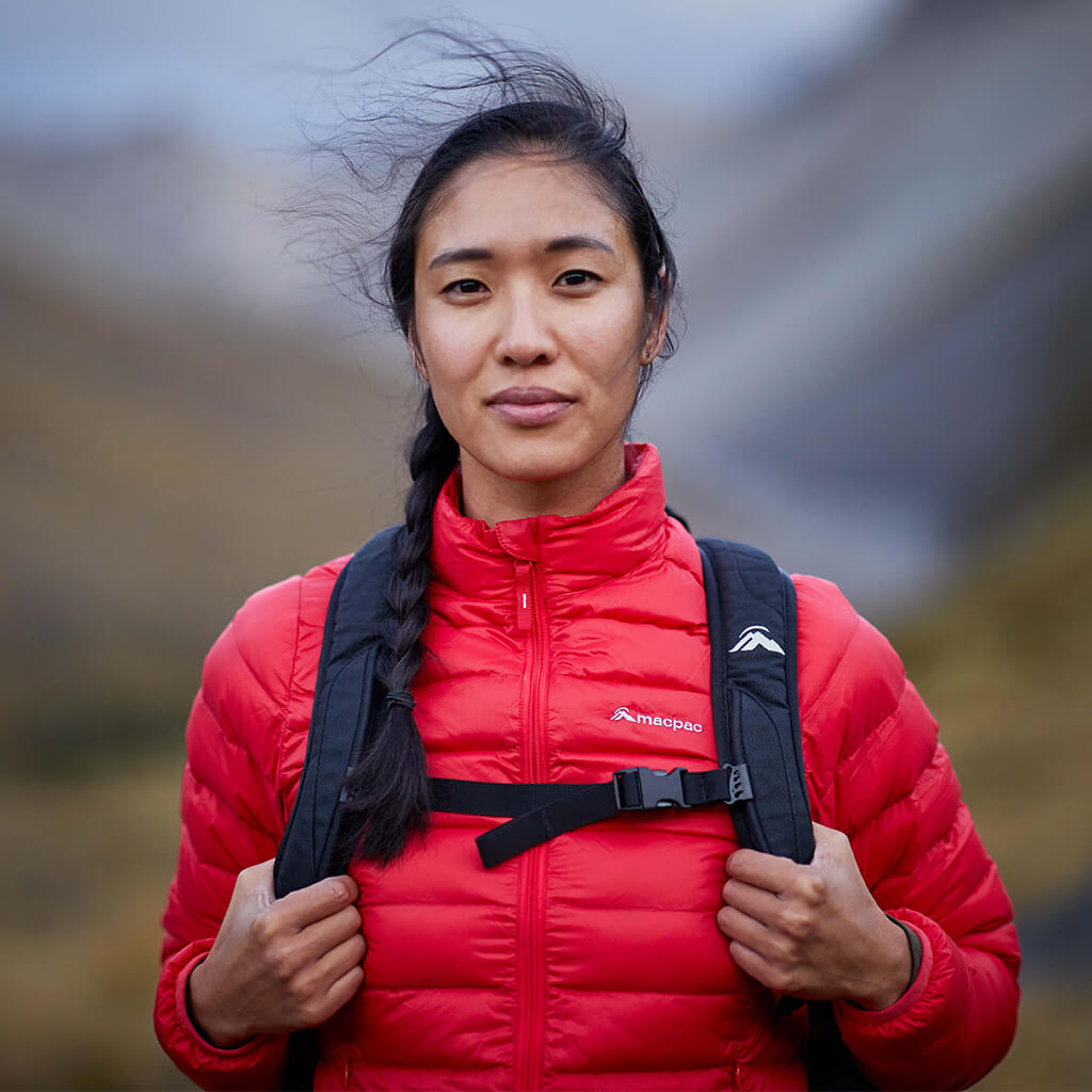 Woman wearing a bright red uber jacket holding black backpack straps