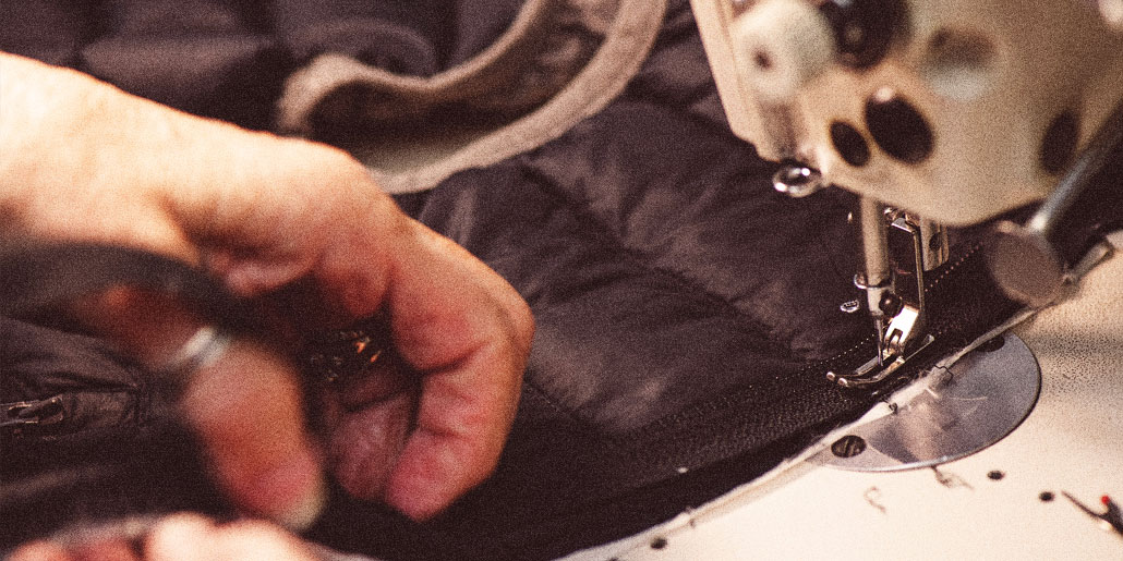 Close up photo of sewing machine, sewing a black jacket