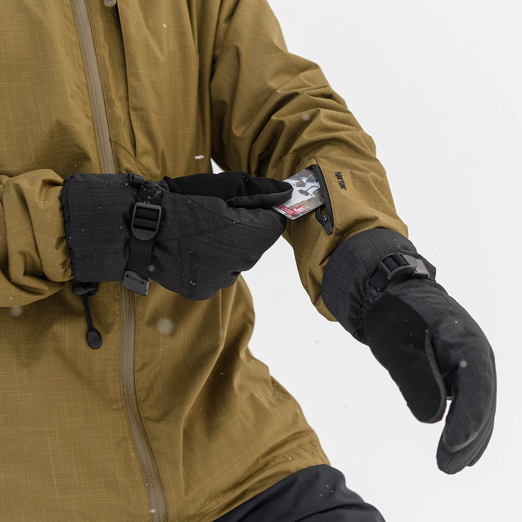 person wearing ski gloves putting a lift pass into their pocket