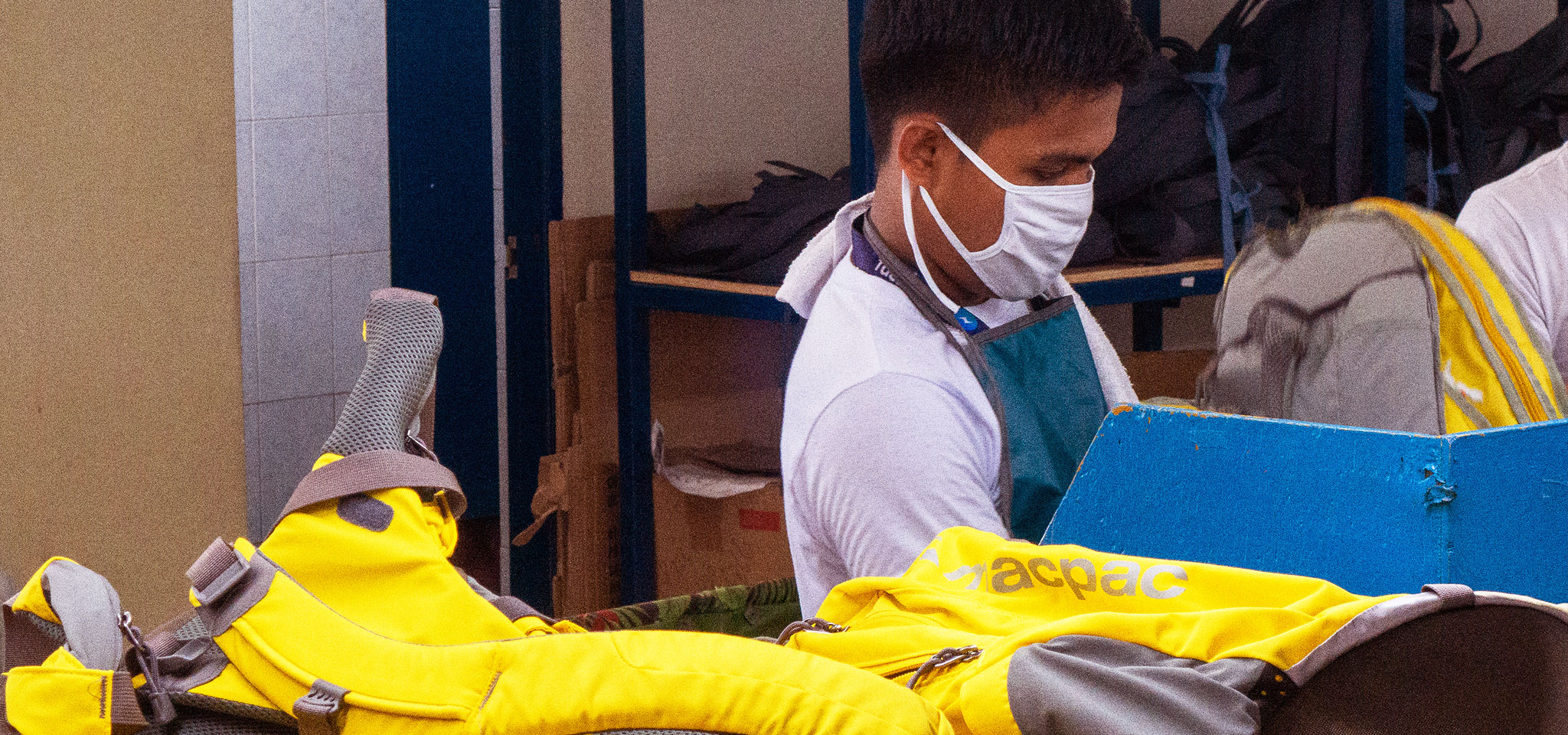 Man wearing facemask inspecting a yellow macpac pac at a factory.