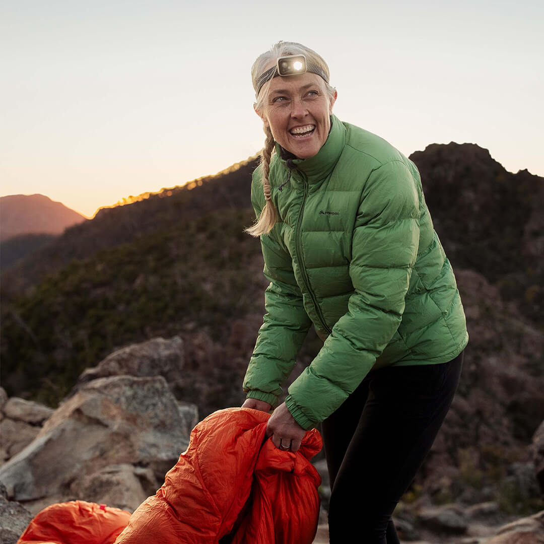 Caro Ryan packing a sleeping bag at a outdoor campsite