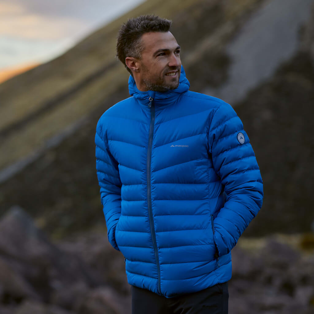 A man wearing a bright blue macpac Mercury jacket on a shady day