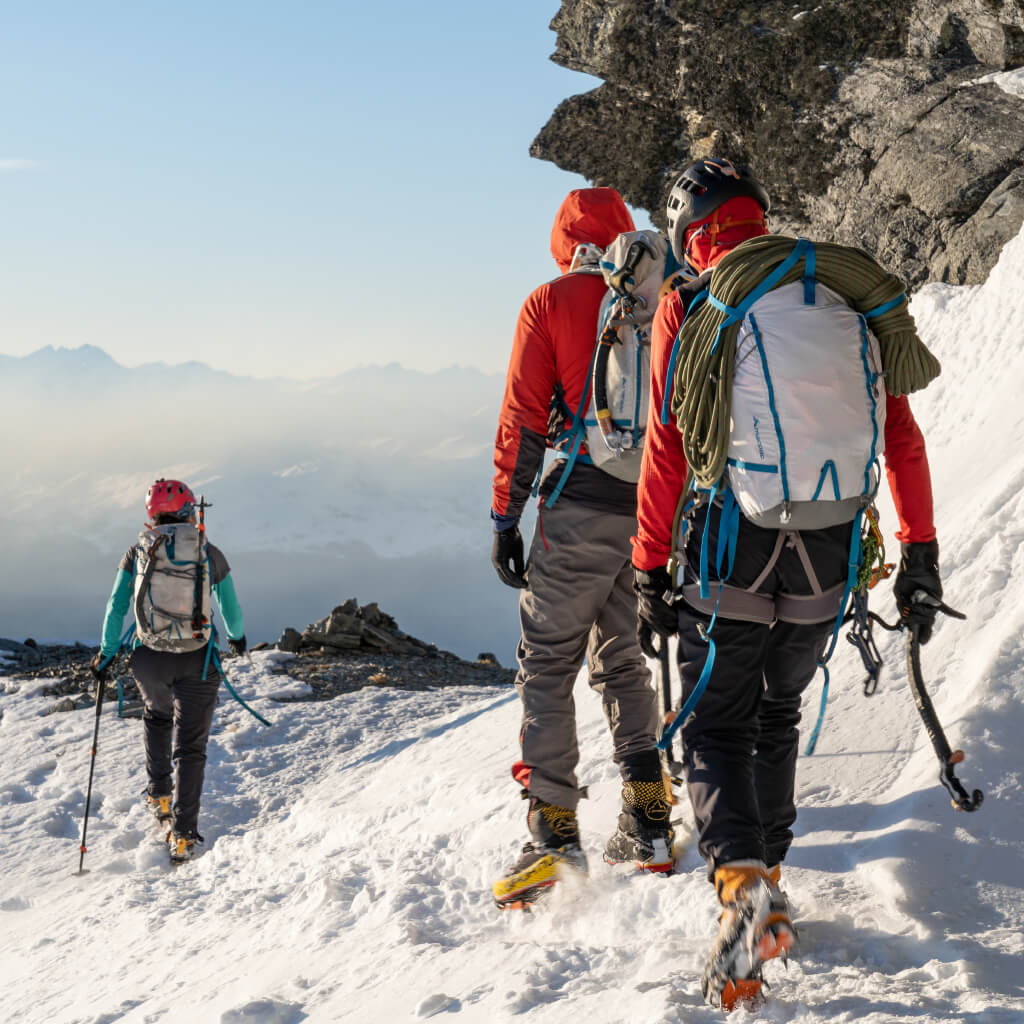 Woman Climbing with Ice axes wearing blue Macpac Jacket and Pack