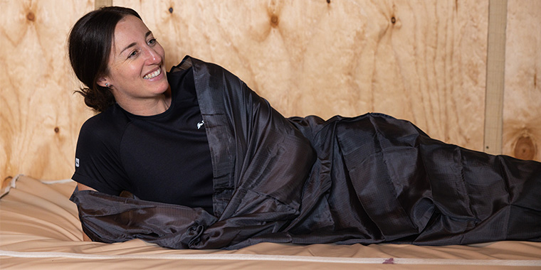 Person packing up black Sleeping Bag in compression sack