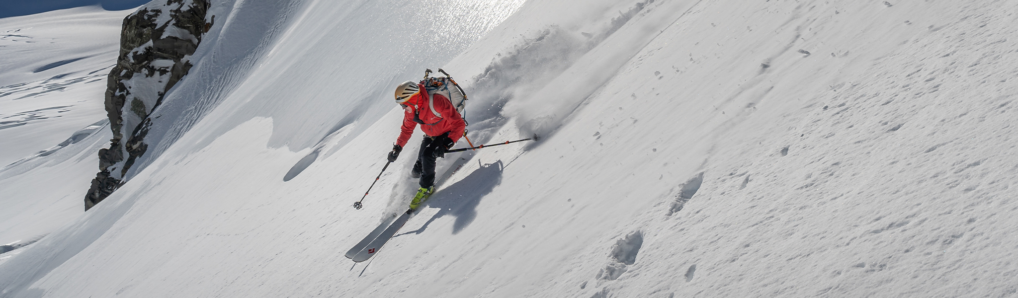 Person sking down very steep slope wearing bright orange jacket